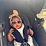 baby, stroller, sunglasses, headband, bow, infant, child, seat_belt, sunlight, outdoor, cute, fashion, portrait, baby_clothes, summer, shade, relaxed, hands, face, infant_care