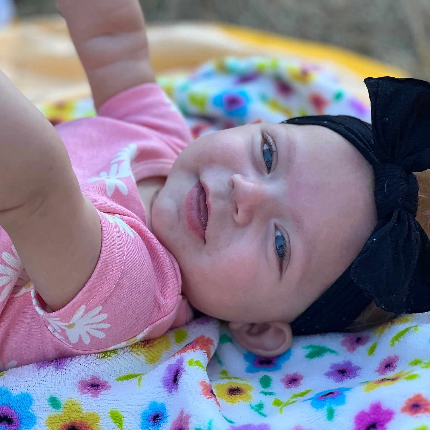 Xzanna joined the competition — help win amazing prizes! baby, black_headband, blanket, blue_eyes, bow, child, colorful, cute, face, floral_pattern, happy, head, infant, lying_down, outdoor, pink_clothing, playful, portrait, skin, smile