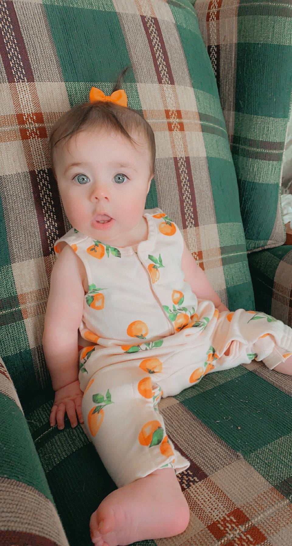 Lakelyn is registered to the contest to win money with this photo: baby, baby_toddler_clothing, chair, cheek, comfort, dress, eye, face, green, head, human_body, lap, orange, pattern, person, pink, skin, sleeve, surprise, tartan