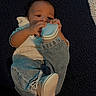 Ezekiel is registered to the contest to win money with this photo: baby, infant, child, portrait, lying_down, sippy_cup, drinking, hands, face, eyes, denim, jeans, sneakers, clothing, rug, indoor, carpet, casual, dark_background, photography