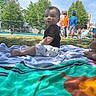 Elias is registered to the contest to win money with this photo: toddler, child, outdoor, park, grass, towel, people, summer, sunny, trees, clothing, boy, sitting, daytime, casual, relaxing, play, nature, family, recreation