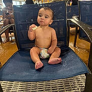 Elias joined the competition — help win amazing prizes! baby, child, diaper, chair, indoor, water_park, pool_area, snack, seated, wet_floor, wooden_beams, people, casual, candid, blue_chair, footwear, person, relaxed, eating, infant