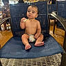 baby, child, diaper, chair, indoor, water_park, pool_area, snack, seated, wet_floor, wooden_beams, people, casual, candid, blue_chair, footwear, person, relaxed, eating, infant