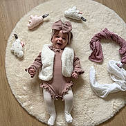 Jade a rejoint le concours — aidez-le/la à gagner de superbes lots ! baby, infant, smiling, headband, vest, tights, plush_toys, cloud_toys, round_rug, wooden_floor, cozy_clothing, child, happy, lying_down, soft_texture, indoor, cute, fashion, accessories, playtime