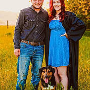 Bear is registered to the contest to win money with this photo: belt, blue_dress, casual_clothing, celebration, dog, field, graduation_cap, graduation_gown, grass, happy, jeans, man, nature, outdoor, pet, portrait, smiling, sunlight, sunset, woman