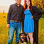 belt, blue_dress, casual_clothing, celebration, dog, field, graduation_cap, graduation_gown, grass, happy, jeans, man, nature, outdoor, pet, portrait, smiling, sunlight, sunset, woman