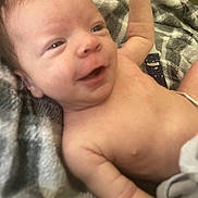 Jake is registered to the contest to win money with this photo: arm, baby, blanket, closeup, cute, expression, face, happy, human, indoors, infant, lying_down, newborn, pattern, portrait, relaxing, skin, smiling, soft_light, young_child