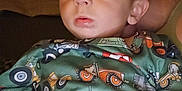 Hudson is registered to the contest to win money with this photo: toddler, child, face, eyes, clothing, pattern, tractor, indoor, portrait, curious, warm_light, sitting, young_child, baby, person, cute, expression, pajamas, fabric, closeup