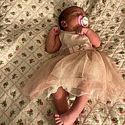 Ruby is registered to the contest to win money with this photo: baby, sleeping, dress, pacifier, blanket, floral_pattern, infant, cute, peaceful, toddler, feet, crossed_legs, bedroom, soft_lighting, pink, fabric, quilt, child, newborn, resting