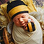newborn, baby, swaddled, blanket, bee_hat, plush_toy, sleeping, pillow, wooden_floor, cute, infant, soft_texture, yellow, black, white, child, portrait, cozy, peaceful, resting