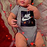 baby, infant, onesie, nike, socks, blanket, heart_effects, cute, chubby, indoor, portrait, child, young, fashion, laying_down, cozy, soft_texture, adorable, casual, relaxed