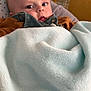 baby, blanket, couch, water_bottle, face, infant, indoors, clothing, soft_texture, curious, resting, yellow_furniture, child, portrait, comfort, cozy, looking, young, casual, home