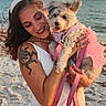 person, dog, beach, ocean, sand, white_dress, pink_leash, tattoo, smile, sunset, horizon, pet, holding, manicure, hairband, necklace, small_dog, tutu, waves, fur