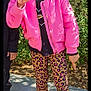 child, girl, smiling, peace_sign, pink_jacket, leopard_print, leggings, sneakers, outdoor, sunny, greenery, hair_buns, happy, casual_clothing, playful, portrait, standing, daylight, nature, fashion