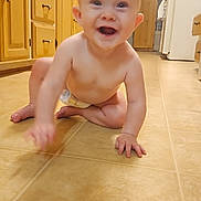 Janie is registered to the contest to win money with this photo: baby, crawling, kitchen, floor, smiling, diaper, child, wooden_cabinets, refrigerator, magnets, photos, tile_floor, happy, indoor, person, candid, cute, young_child, tongue_out, hands