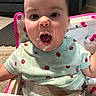 Sunflower is registered to the contest to win money with this photo: baby, child, messy_face, high_chair, food, mouth_open, ladybug_pattern, shirt, carpet, couch, living_room, seatbelt, seat, indoor, person, cute, expression, feeding, infant, young_child
