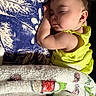 baby, sleeping, blanket, pillow, yellow_clothing, earrings, indoor, closeup, peaceful, child, face, soft_texture, resting, infant, portrait, cozy, cute, toddler, home, comfort
