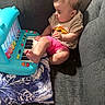 baby, child, toy_piano, blue_toy, colorful, couch, gray_couch, pillow, foot, hand, shorts, tshirt, indoor, playing, curious, infant, person, furniture, happy, music_toy