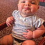 Avalyn is registered to the contest to win money with this photo: baby, child, infant, high_chair, wooden_furniture, floral_clothing, onesie, chubby_cheeks, cute, smiling, indoor, restaurant, booth_seating, carpet, table, person, portrait, sitting, hand, foot