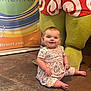 baby, child, smiling, floor, dress, floral_pattern, mascot, costume, legs, tile, indoor, colorful, background, person, happy, seated, cute, infant, playful, advertisement