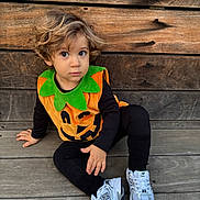 Antoine-Marie participe au concours pour gagner de l'argent avec cette photo : toddler, child, pumpkin_costume, halloween, sitting, wooden_floor, wooden_wall, curly_hair, white_sneakers, black_clothing, costume, cute, portrait, indoors, person, young_child, casual, holiday, seasonal, festive