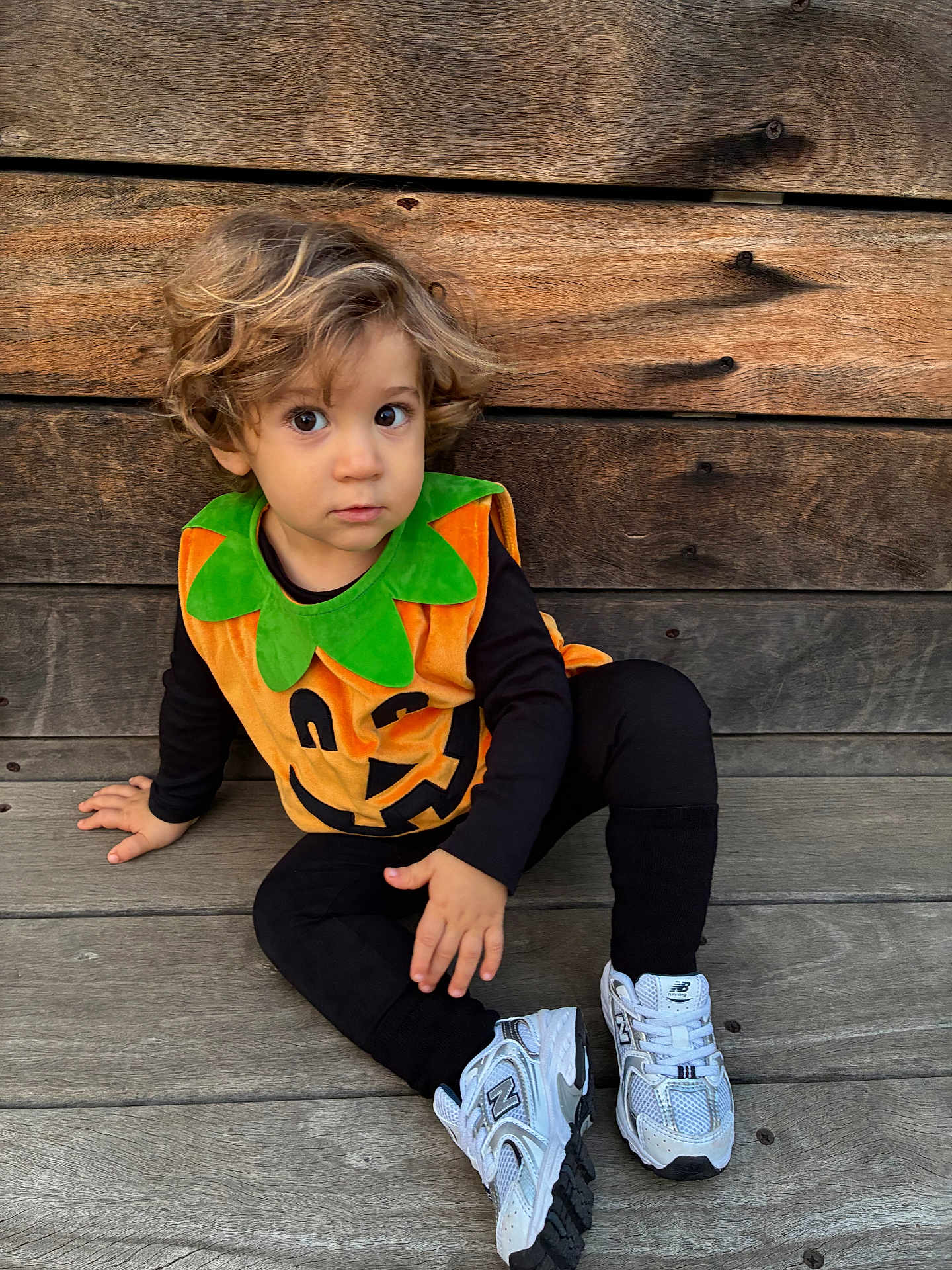 Antoine-Marie participe au concours pour gagner de l'argent avec cette photo : toddler, child, pumpkin_costume, halloween, sitting, wooden_floor, wooden_wall, curly_hair, white_sneakers, black_clothing, costume, cute, portrait, indoors, person, young_child, casual, holiday, seasonal, festive