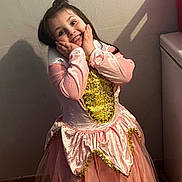 Amaraa a rejoint le concours — aidez-le/la à gagner de superbes lots ! child, girl, smile, princess_dress, pink_dress, costume, hands_on_cheeks, long_hair, indoor, wall, shadow, red_bin, tile_floor, posing, happy, gold_trim, ruffled_skirt, portrait, playtime, cute