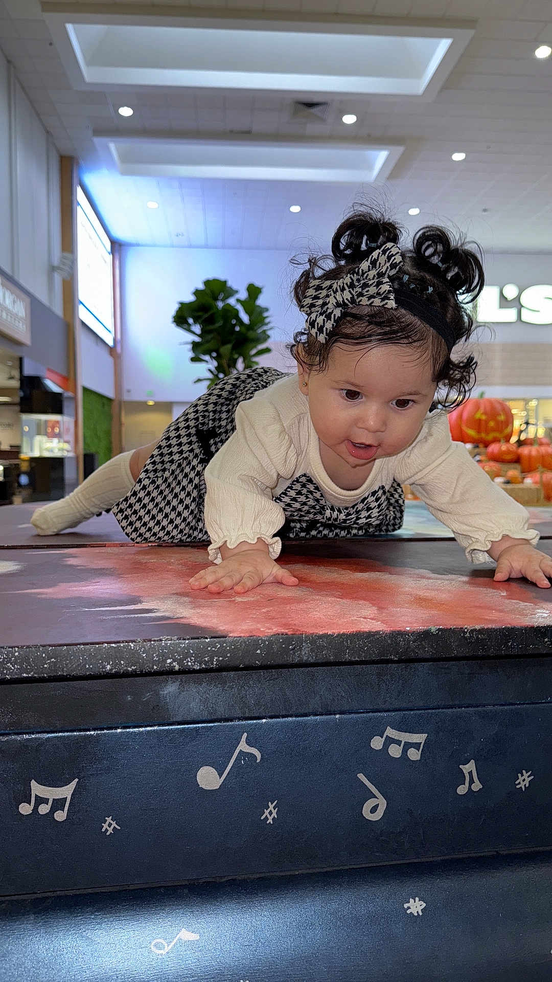 Julieth Camila Novoa joined the competition — help win amazing prizes! toddler, child, indoor, crawling, curly_hair, bow, patterned_clothing, music_notes, pumpkin, mall, plant, table, face, hands, headband, long_sleeve, floor, lighting, curiosity, person