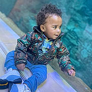 Malachi is registered to the contest to win money with this photo: blackhair, bodypart, boy, child, clothing, coat, crawling, face, footwear, hair, head, jacket, male, pants, person, photography, portrait, shoe, sitting, sleeve