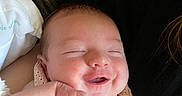 Aurora joined the competition — help win amazing prizes! baby, smile, hands, blanket, face, infant, sleeping, person, closeup, cute, clothing, resting, skin, head, cheeks, pattern, striped_background, black_shirt, red_text, cozy