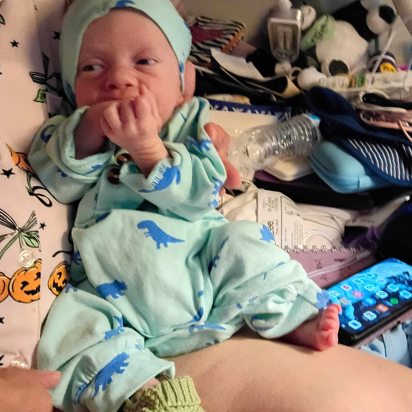 Desmond joined the competition — help win amazing prizes! baby, newborn, infant, child, portrait, sitting, pajamas, dinosaur_pattern, mint_green, baby_hat, hand, finger, smiling, bed, blanket, stuffed_animal, toy, smartphone, indoor, nursery
