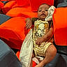 Mason joined the competition — help win amazing prizes! baby, infant, child, portrait, sitting, theater_seats, red_seats, onesie, elephant_print, striped_clothing, blanket, cloth, indoor, theater, seated, barefoot, face, arms, legs, photography