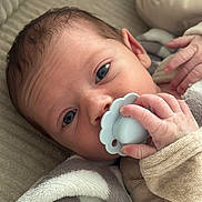 Maë participe au concours pour gagner de l'argent avec cette photo : baby, pacifier, hand, face, blue_eyes, blanket, cozy, infant, closeup, skin, sleepwear, cute, newborn, soft, portrait, child, fingers, resting, indoors, comfort