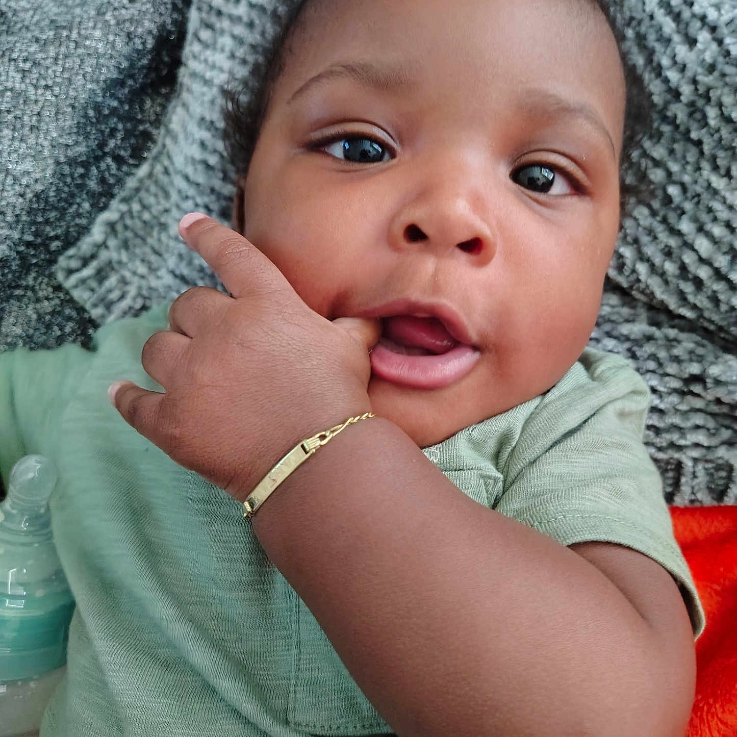 Tahjae is registered to the contest to win money with this photo: baby, blanket, bottle, bracelet, child, closeup, clothing, cute, expression, eyes, face, finger, green_shirt, hand, indoors, infant, portrait, skin, soft, texture