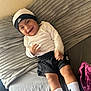 baby, child, smiling, laughing, nike, hat, shorts, socks, bed, blanket, pillow, plush, indoors, happy, person, clothing, footwear, cozy, home, casual