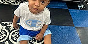 Niko is registered to the contest to win money with this photo: toddler, child, indoor, store, floor, sneakers, clothing, shorts, tshirt, shelf, snacks, candy, curious, patterned_floor, shopping, retail, person, young_child, footwear, expression