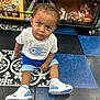 toddler, child, indoor, store, floor, sneakers, clothing, shorts, tshirt, shelf, snacks, candy, curious, patterned_floor, shopping, retail, person, young_child, footwear, expression