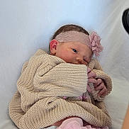 Hadley is registered to the contest to win money with this photo: baby, infant, headband, flower, knit_sweater, pink, blanket, sleepwear, cute, newborn, soft, cozy, portrait, small_hands, child, wrapped, resting, indoors, fabric, toddler