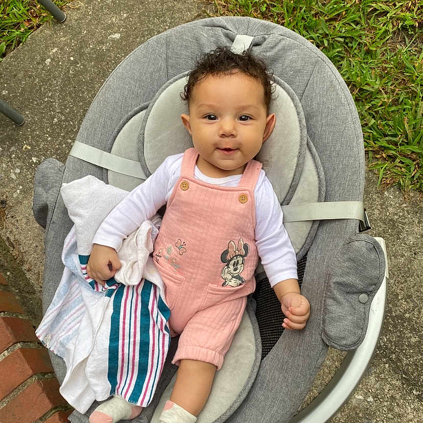 Azlynn is registered to the contest to win money with this photo: baby, baby_rocker, brick, child, concrete, curly_hair, cute, grass, gray_cushion, infant, minnie_mouse, outdoor, person, pink_overall, seated, smiling, socks, striped_cloth, toddler, white_shirt
