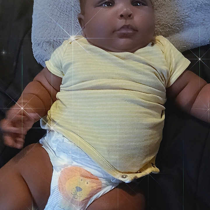 Jah'Carrie is registered to the contest to win money with this photo: arm, baby, blanket, child, chubby, comfort, cute, diaper, face, indoors, infant, leg, lying_down, portrait, relaxing, skin, smiling, soft_texture, sparkle_effect, yellow_shirt