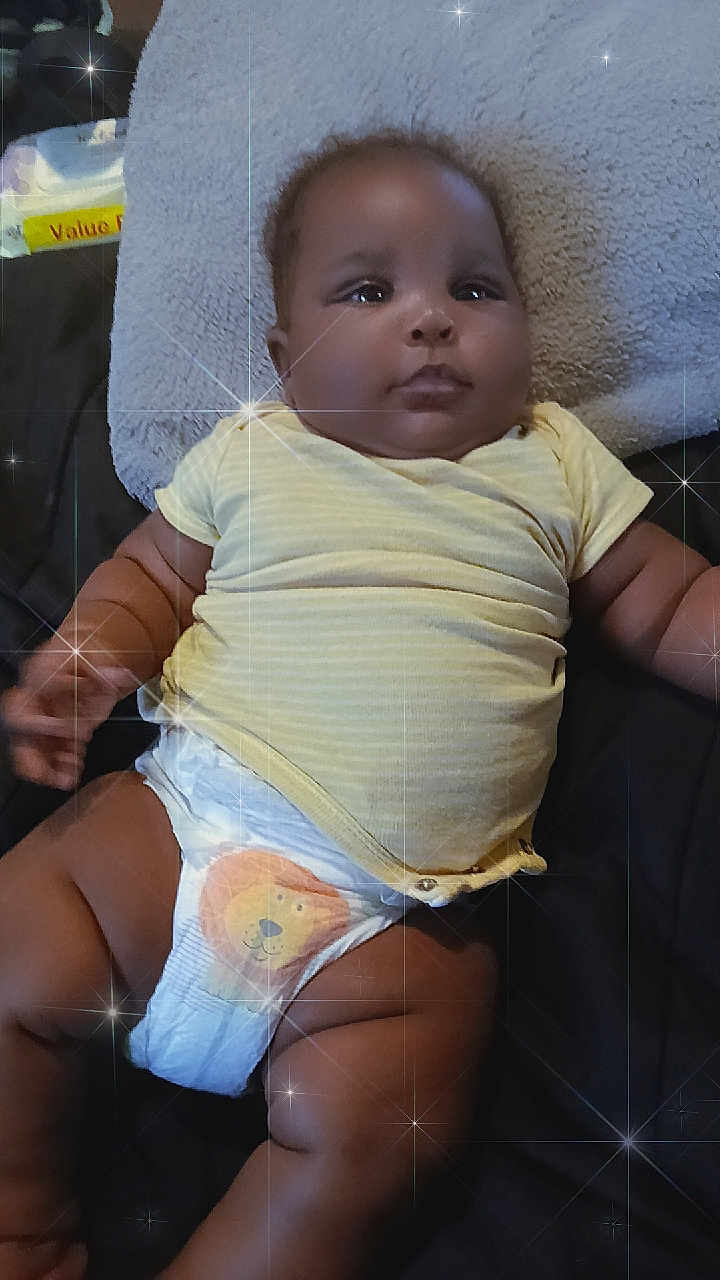 Jah'Carrie is registered to the contest to win money with this photo: baby, infant, diaper, yellow_shirt, lying_down, blanket, soft_texture, sparkle_effect, cute, chubby, child, indoors, comfort, relaxing, portrait, smiling, skin, face, arm, leg