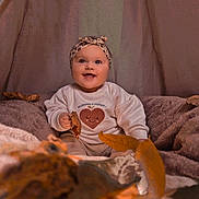 Amélia participe au concours pour gagner de l'argent avec cette photo : baby, smiling, headband, autumn_leaves, blanket, cozy, indoor, child, cute, sitting, happy, portrait, clothing, warm_colors, fall, infant, soft_texture, face, person, seasonal