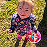 basket, casual_clothing, child, colorful_eggs, cute, daylight, flower_pattern, girl, grass, happy, nature, outdoor, play, portrait, shadow, smiling, spring, standing, sunlight, sweater