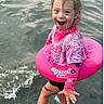 Emersyn is registered to the contest to win money with this photo: child, smiling, water, swimming, float_ring, pink_clothing, happy, outdoor, water_shoes, playful, summer, fun, portrait, young_child, splash, active, cute, joyful, nature, daytime