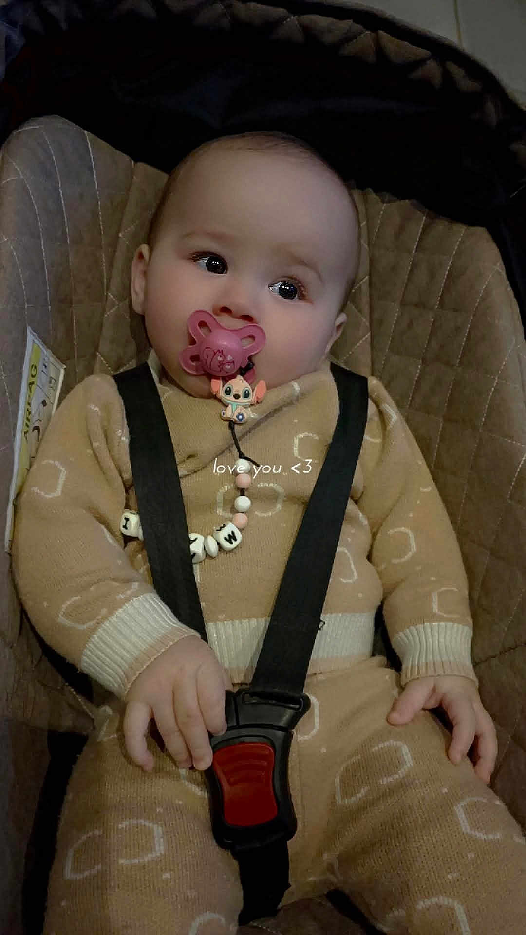 Maria participe au concours pour gagner de l'argent avec cette photo : baby, infant, pacifier, car_seat, seat_belt, buckle, onesie, sweater, bead_chain, toy, closeup, portrait, hand, eyes, looking_up, cozy, fabric, seat_padding, indoor, clip