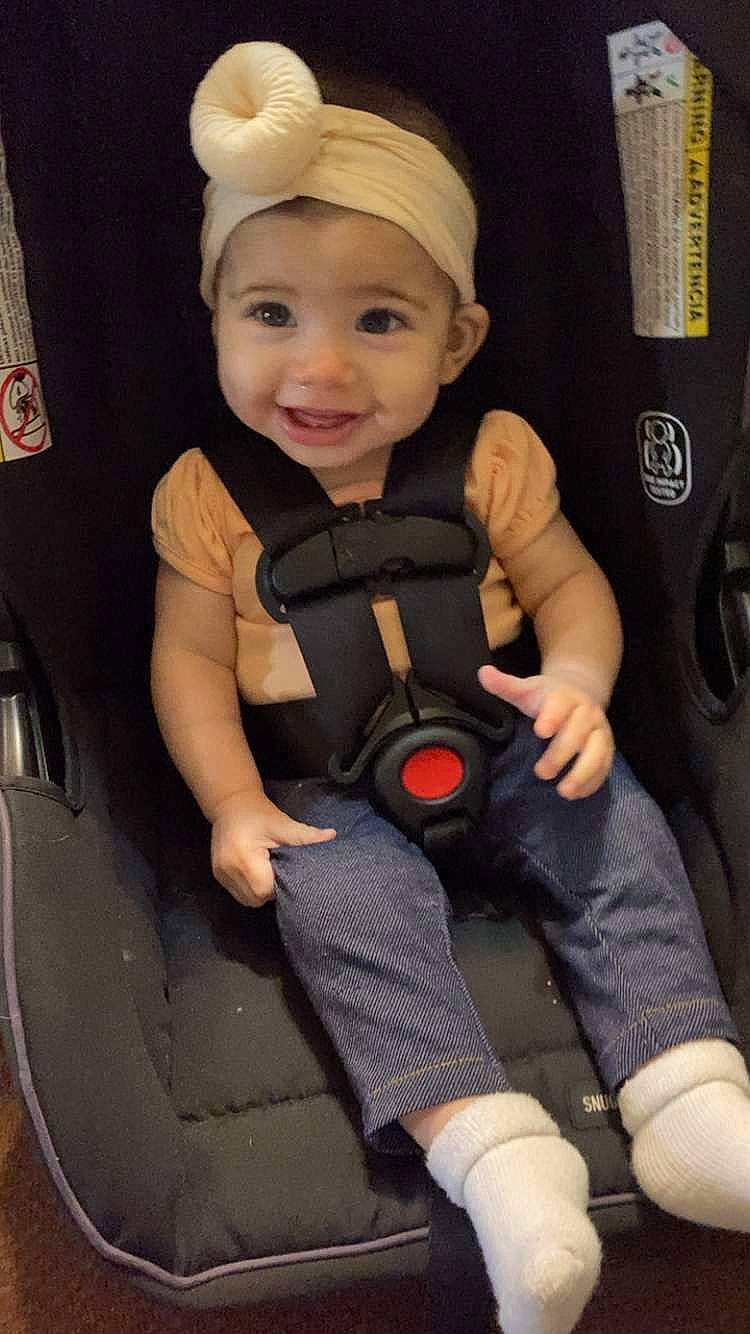 Amelia is registered to the contest to win money with this photo: auto_part, baby, baby_carriage, baby_safety, baby_toddler_clothing, car_seat, cheek, comfort, finger, headwear, joy, knee, person, personal_protective_equipment, product, seat_belt, sitting, skin, smile, thigh