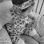 Loumïa participe au concours pour gagner de l'argent avec cette photo : baby, infant, child, crib, cushion, headband, floral, overalls, socks, book, cartoon, bee, pattern, stars, black_and_white, seated, soft_toys, hand, floor, indoors