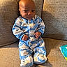 baby, infant, onesie, blue, white, polar_bear_pattern, couch, furniture, texture, clothing, footed_pajamas, indoor, person, cute, small_hands, seated, diapers, soft_lighting, portrait, child