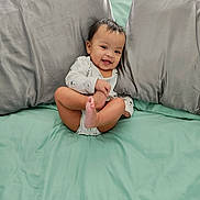 Aaliyah joined the competition — help win amazing prizes! baby, smiling, onesie, bed, pillow, gray_pillow, mint_green_bed, infant, cute, happy, child, foot, hand, indoors, playful, sitting, face, person, cozy, soft