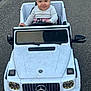 amg, baby, child, childhood, clothing, cute, grinning, head, hood, mercedes, outdoor, pavement, person, play, road, sitting, small_vehicle, smile, toy_car, white_car